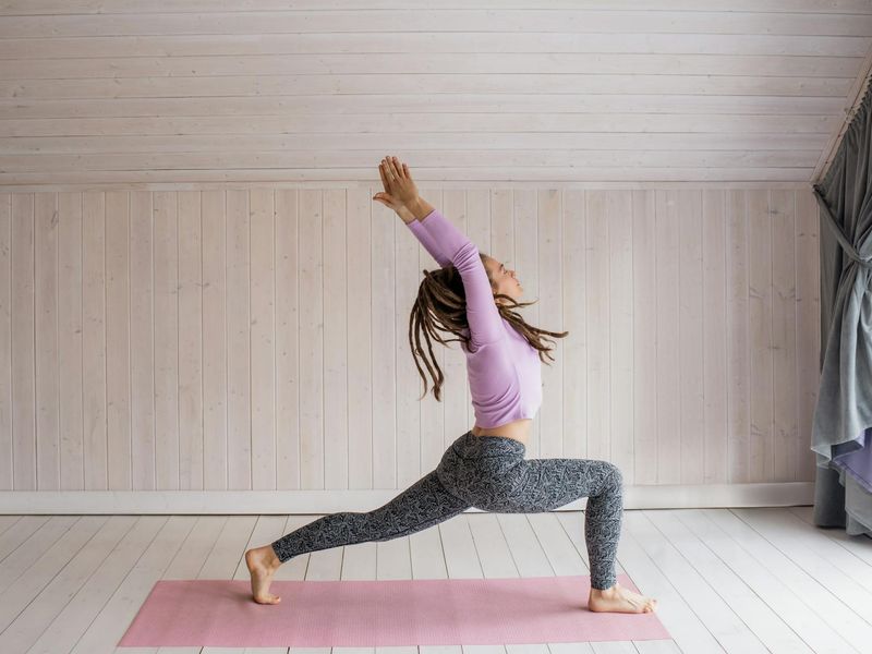 A person performing a flowing yoga sequence in a bright, minimalist room.